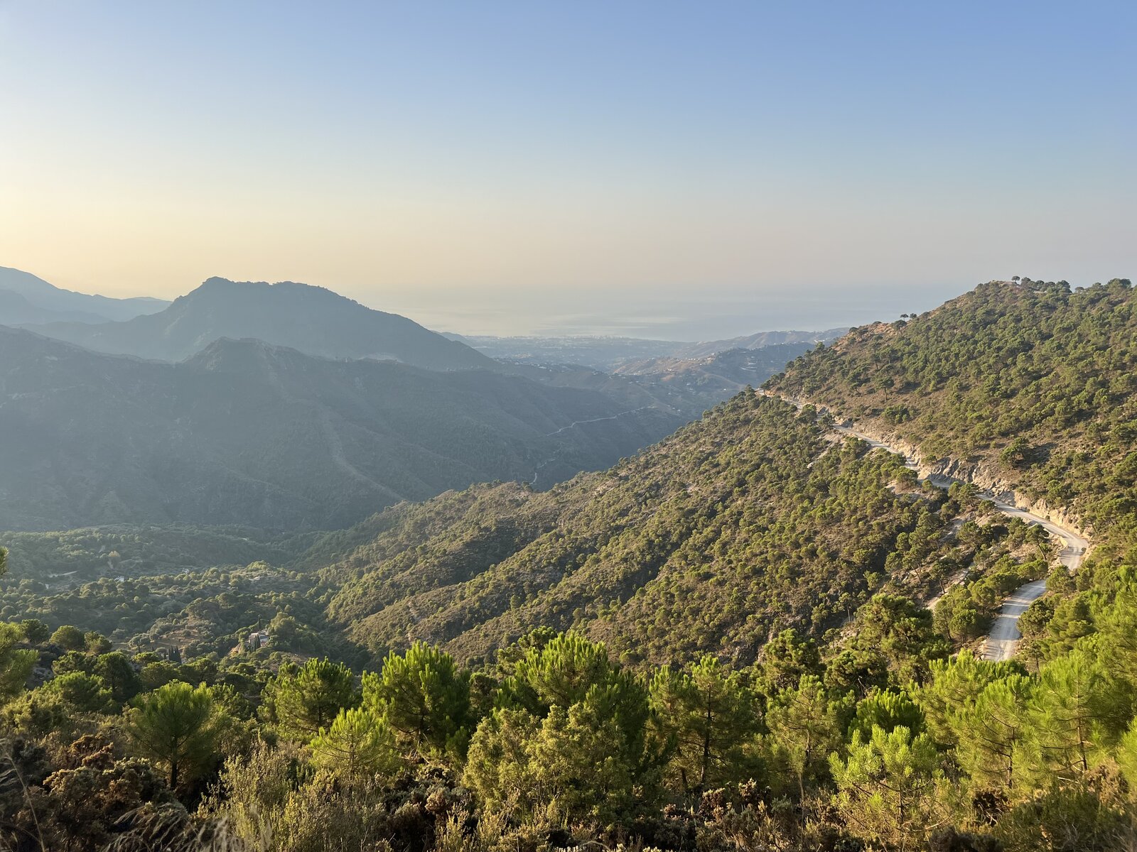 The road south through the mountains of Andalucía at sunset, the Mediterranean visible in the distance.