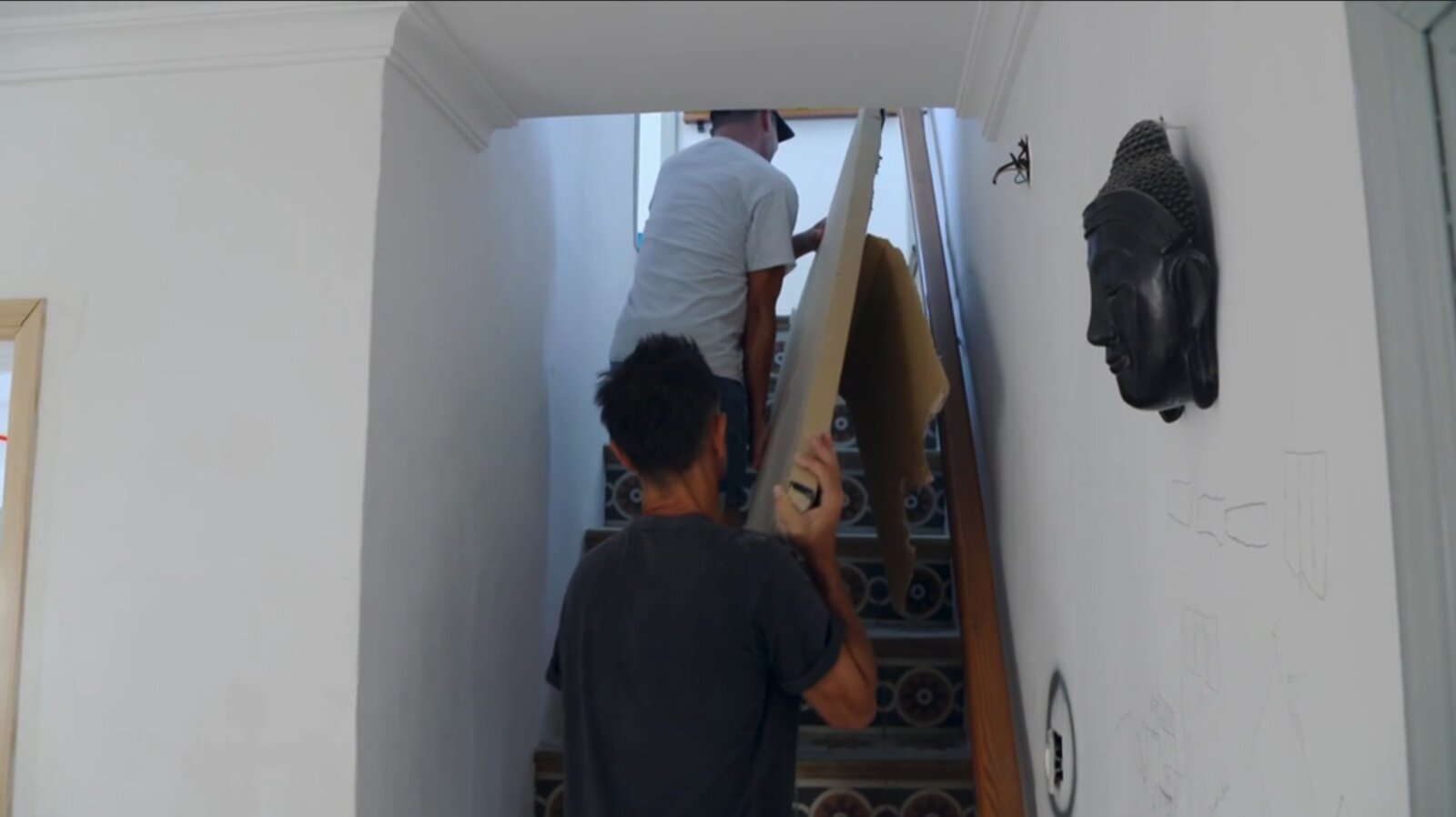 Ian and a worker carrying construction boards up the encaustic-tiled staircase of Casa Jardín during the renovation.